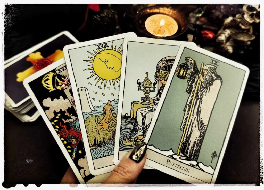 Tarot z 5 kart: Pustelnik, Król Kielichów, Księżyc, Wieża, i Królowa Kielichów na tle świecy i czaszki.